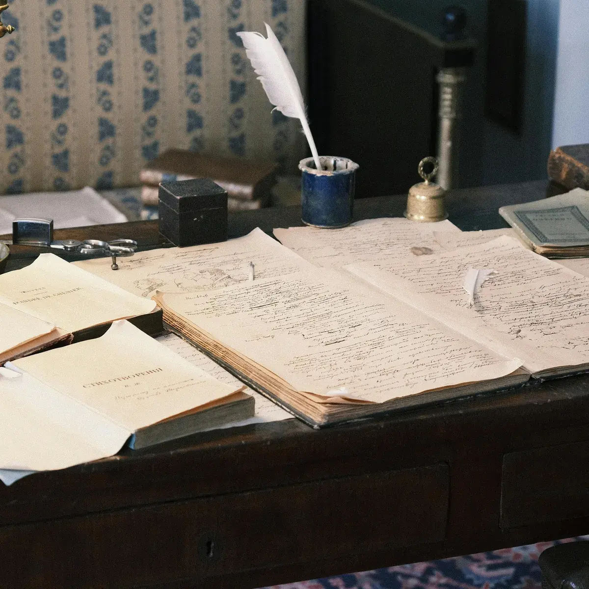 Escrivaninha vintage com livros academicos abertos e papeis manuscritos, luz dourada lateral.