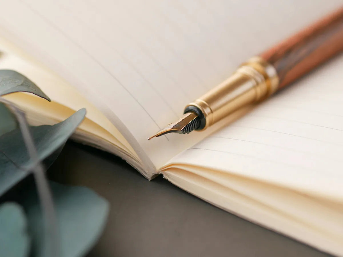 Caneta fonte vintage repousada sobre caderno aberto com linhas elegantes, atmosfera de escrita honesta.